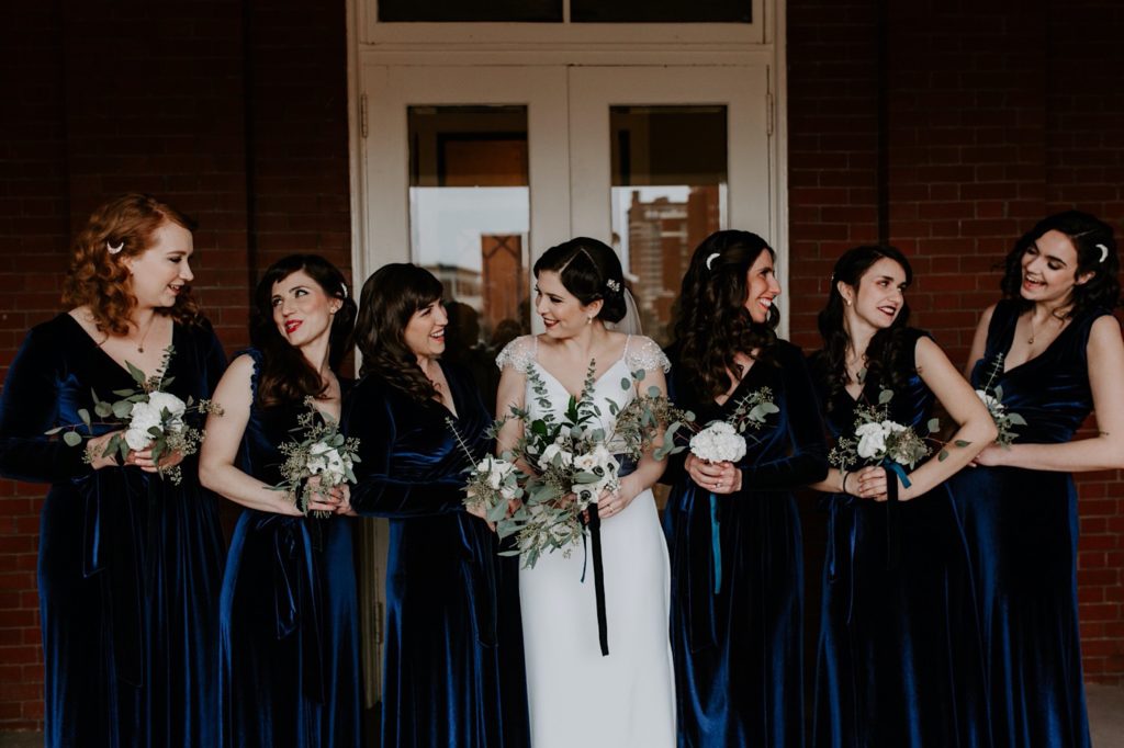 Bridal party smiling and looking at each other at the masonic temple in downtown Asheville 