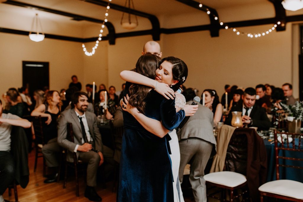 bride hugging her maid of honor during the reception at the Asheville  masonic temple